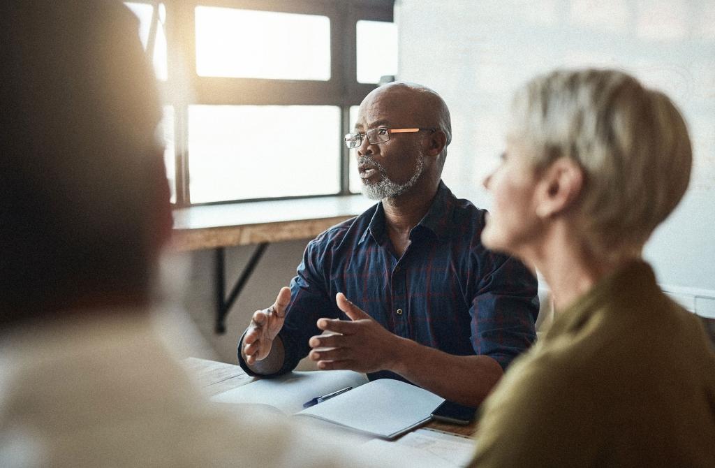 A group of people meeting in a sunlit room. 