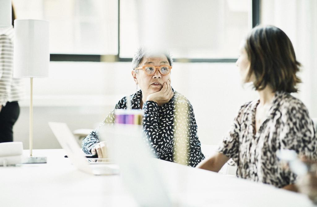 Woman in meeting talks with colleague.