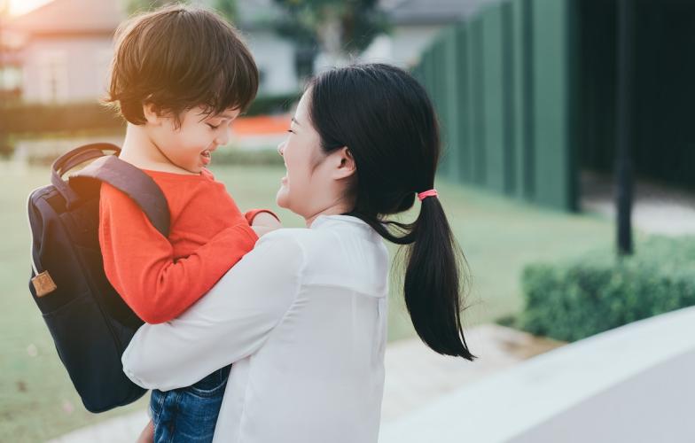 Mom holding child with backpack