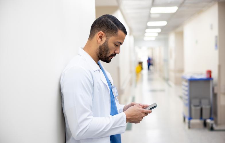Doctor pauses to text in hospital hallway corridor