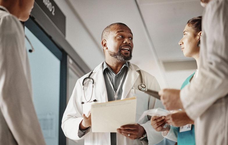 A doctor speaking with three other medical staff in a hospital hallway.