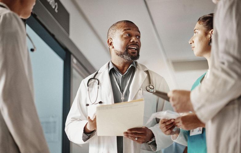 A doctor speaking with three other medical staff in a hospital hallway.