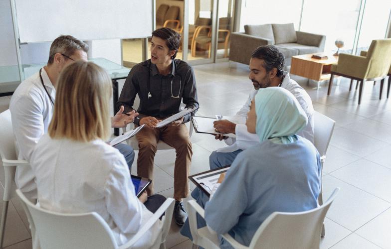 Five doctors sitting in a circle and talking. 
