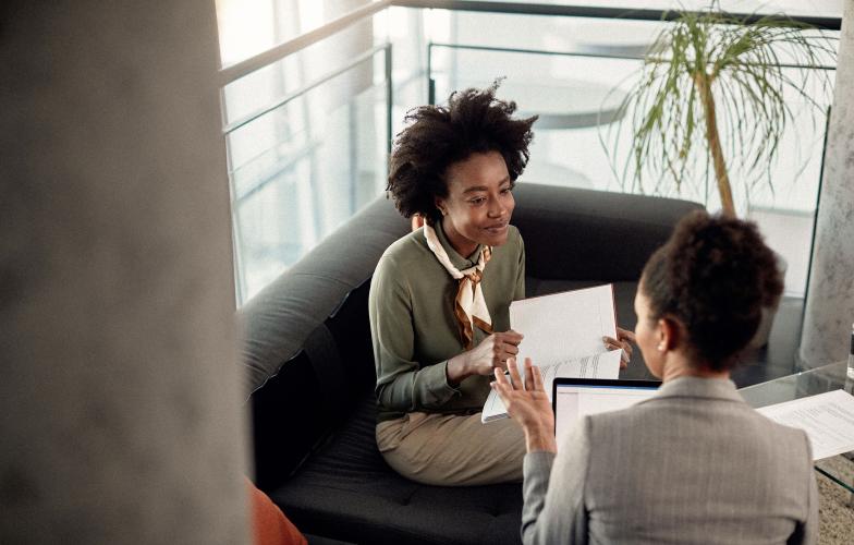 Two people speaking while reviewing documents.