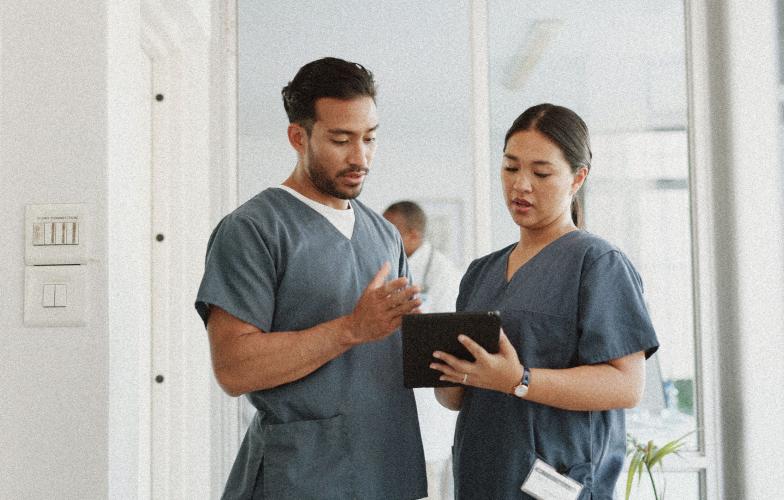 Two nurses looking at an ipad in a clinic. 