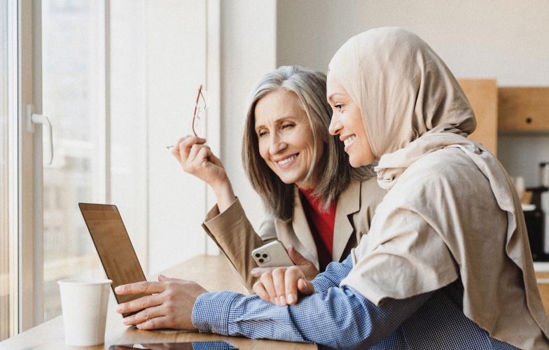 Two individuals looking at a laptop and smiling. 