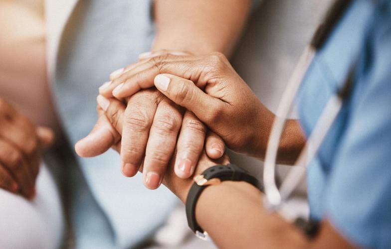 A doctors hands holding a patient's hand between them. 