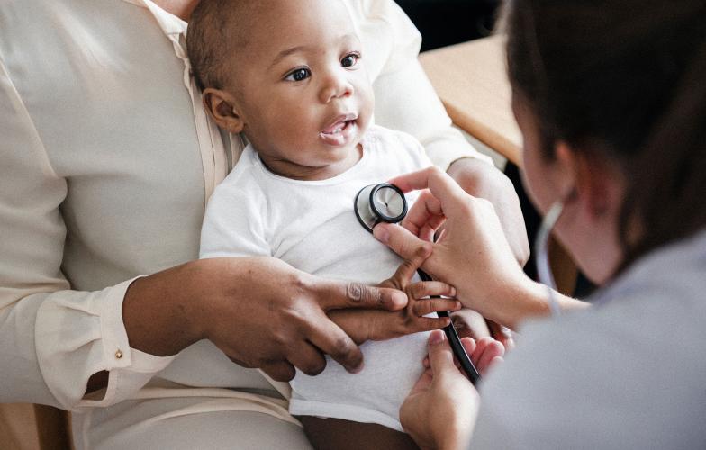 A doctor examining an infant's heart with stethoscope.