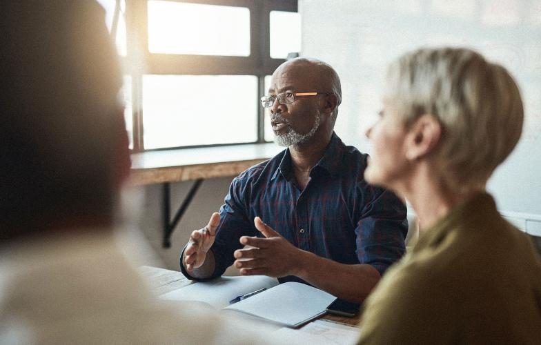 A group of people meeting in a sunlit room. 