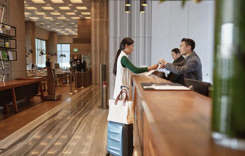 Person standing at the front desk of a hotel checking into their room.