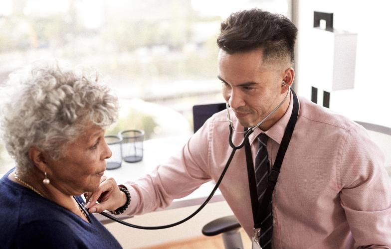 Doctor listening to an elderly patients chest with a stethoscope.