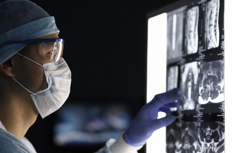 Surgeon looking at a MRI scan in dark OR. 