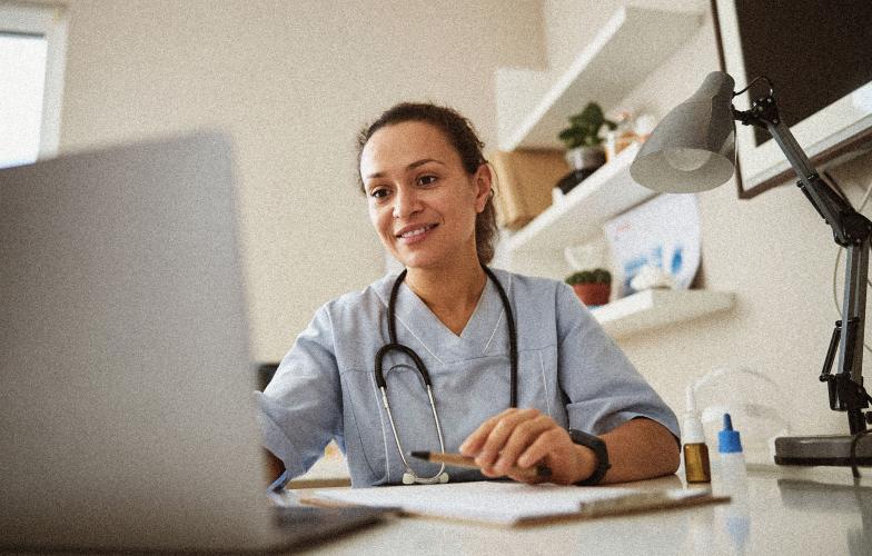 doctor smiling and looking at laptop in office