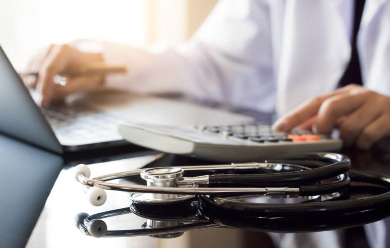 A physician typing on a laptop