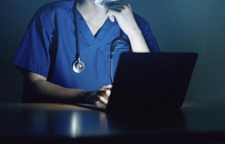 Close up of doctor working on laptop late night.