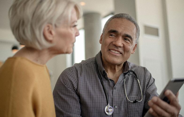 A doctor holding an AI scribe talks with a patient