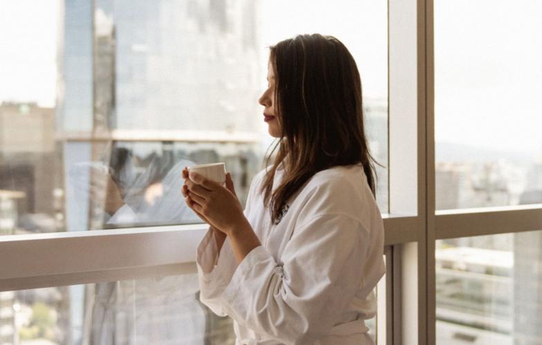 A hotel guest looking out the window of their hotel room
