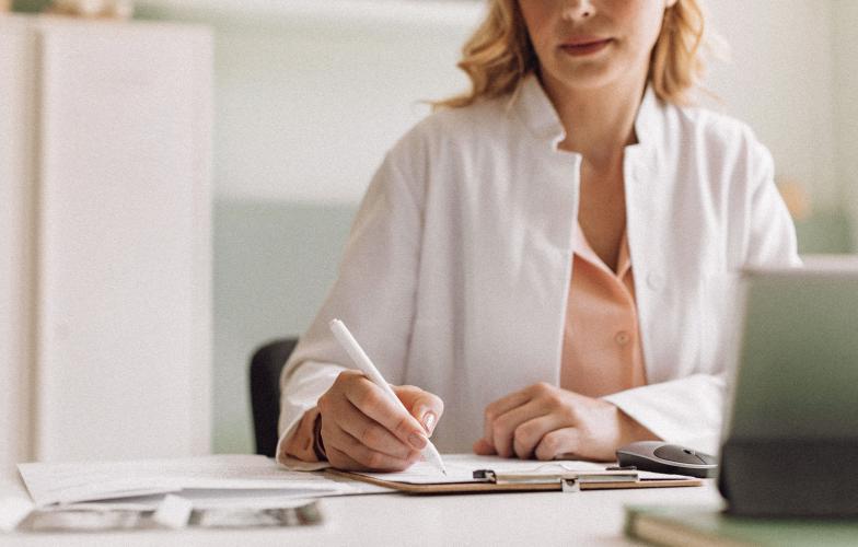 A physician writing a note on their desk