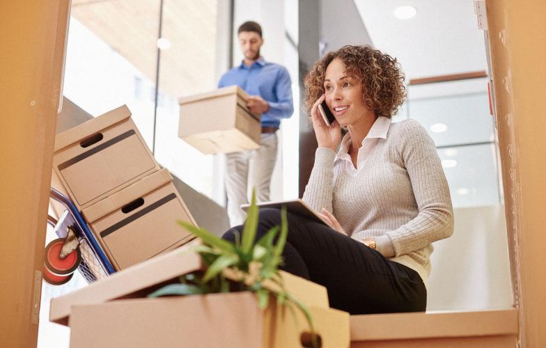 A woman talking on a cell phone amongst moving boxes during an office move