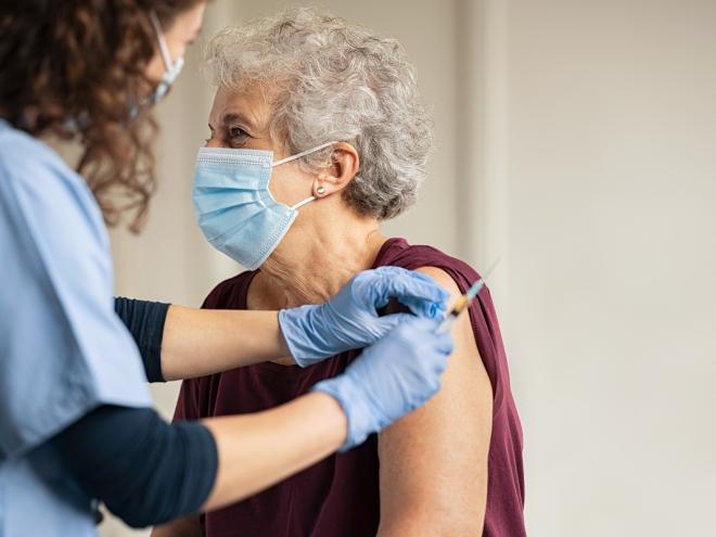 Doctor providing elderly woman COVID vaccine 