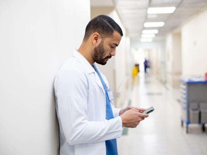 Doctor pauses to text in hospital hallway corridor