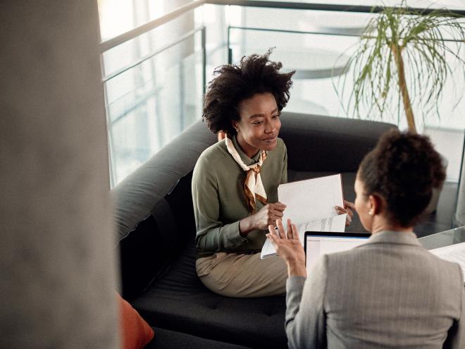 Two people speaking while reviewing documents.