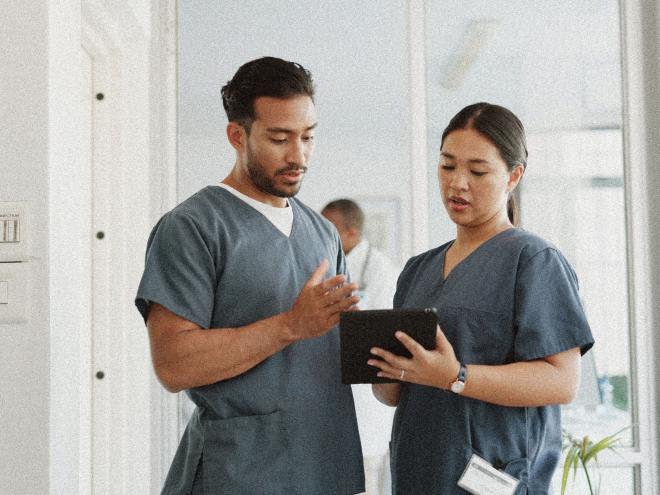 Two nurses looking at an ipad in a clinic. 