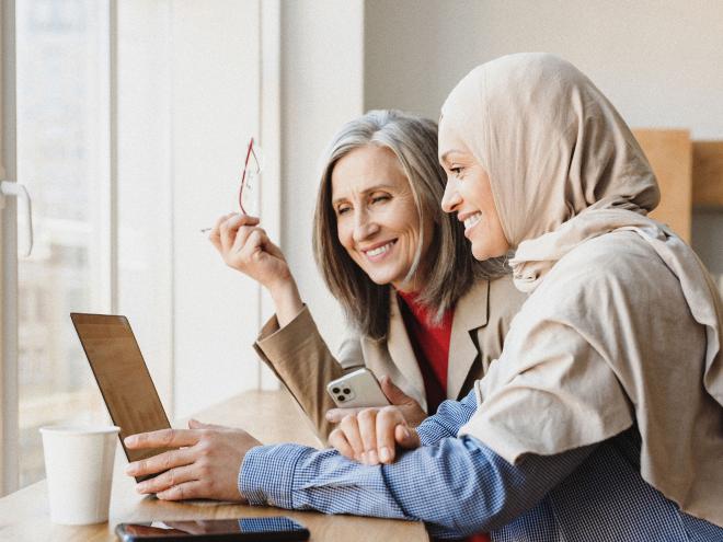 Two individuals looking at a laptop and smiling. 