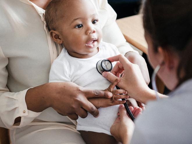 A doctor examining an infant's heart with stethoscope.