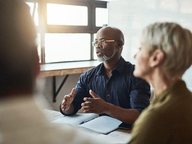A group of people meeting in a sunlit room. 