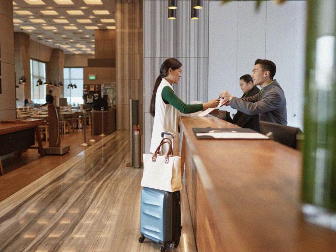 Person standing at the front desk of a hotel checking into their room.