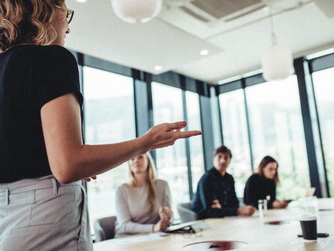 An individual giving a presentation in front of a group in an office.