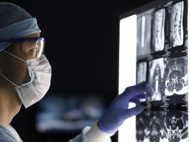 Surgeon looking at a MRI scan in dark OR. 