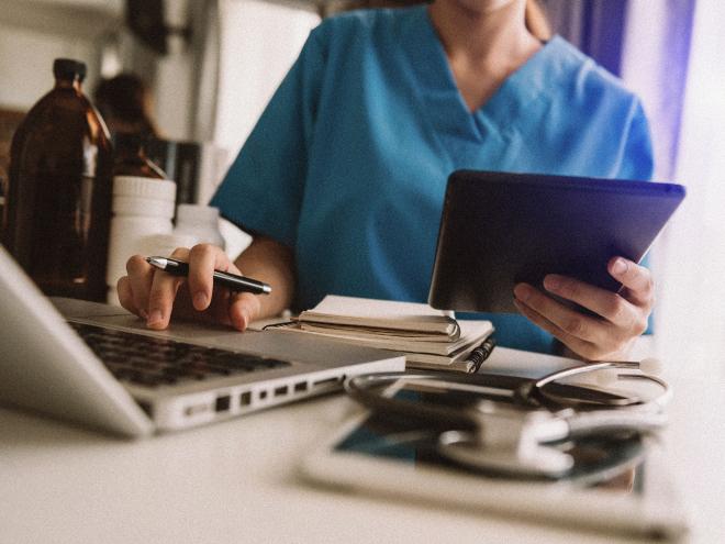 close up doctor working on laptop with iPad