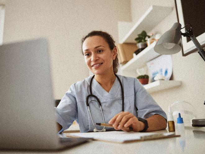 doctor smiling and looking at laptop in office