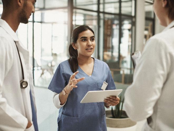 A nurse with an iPad speaking to a small group of young physicians