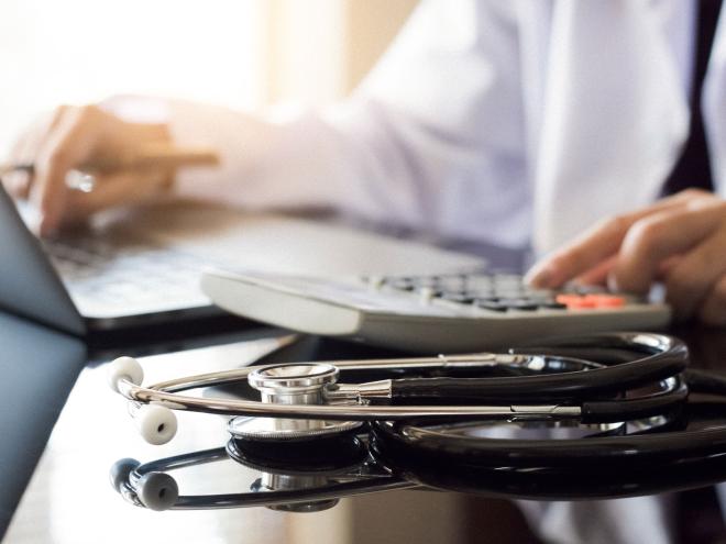 A physician typing on a laptop