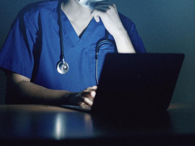 Close up of doctor working on laptop late night.