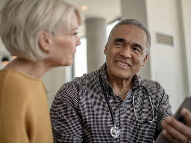A doctor holding an AI scribe talks with a patient