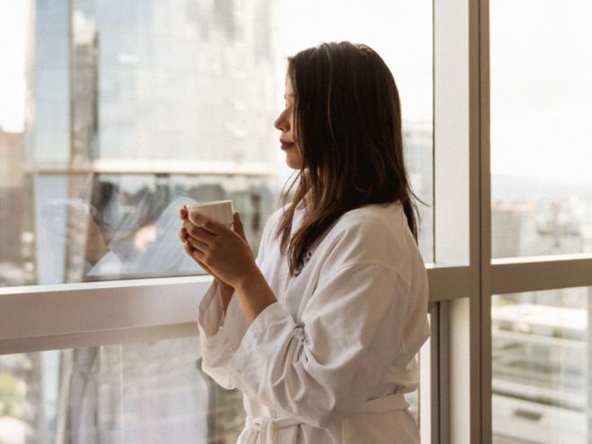 A hotel guest looking out the window of their hotel room