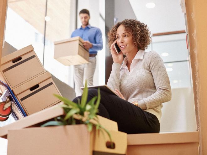 A woman talking on a cell phone amongst moving boxes during an office move
