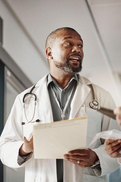 A doctor speaking with three other medical staff in a hospital hallway.
