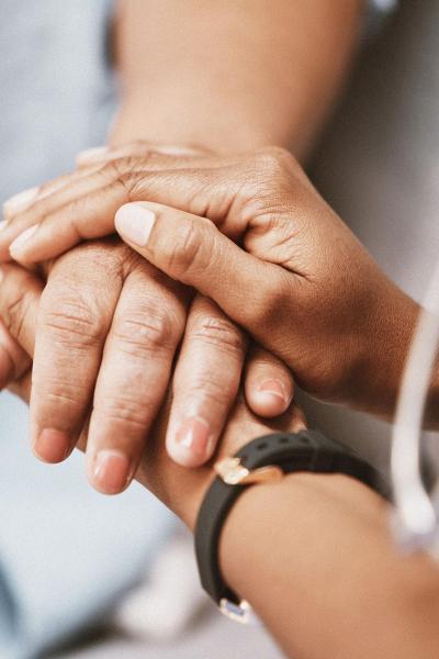 A doctors hands holding a patient's hand between them.