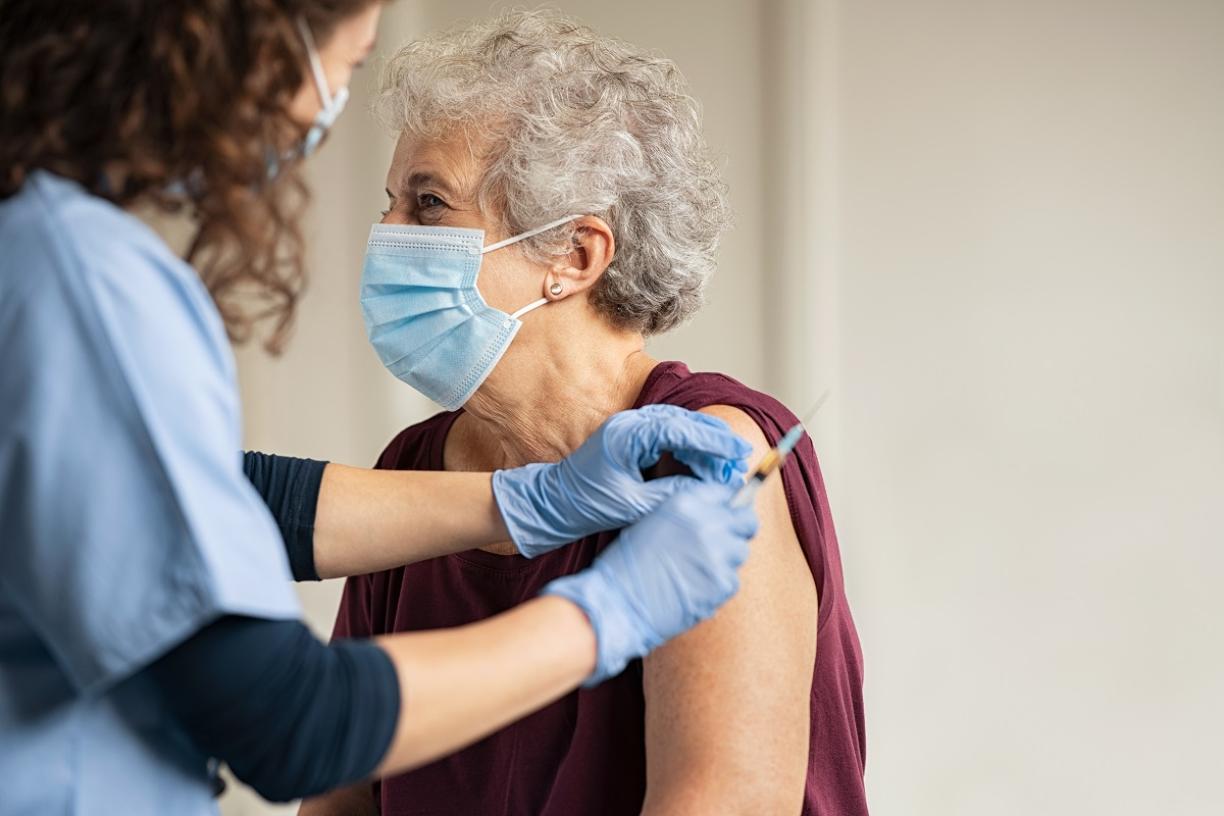 Doctor providing elderly woman COVID vaccine 