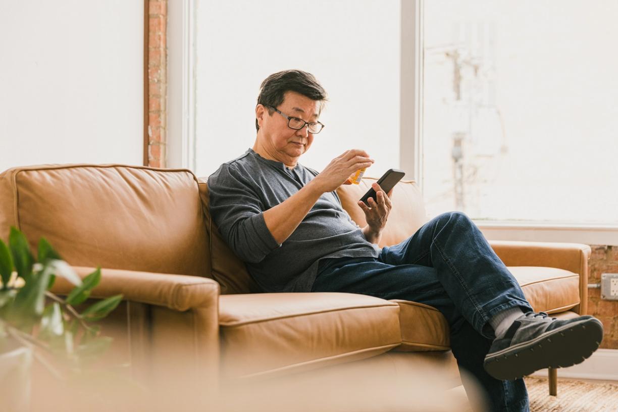 man_on_couch_with_pill_bottle_prescription_on_virtual_call_with_doctor_telemedicine_stock.jpg