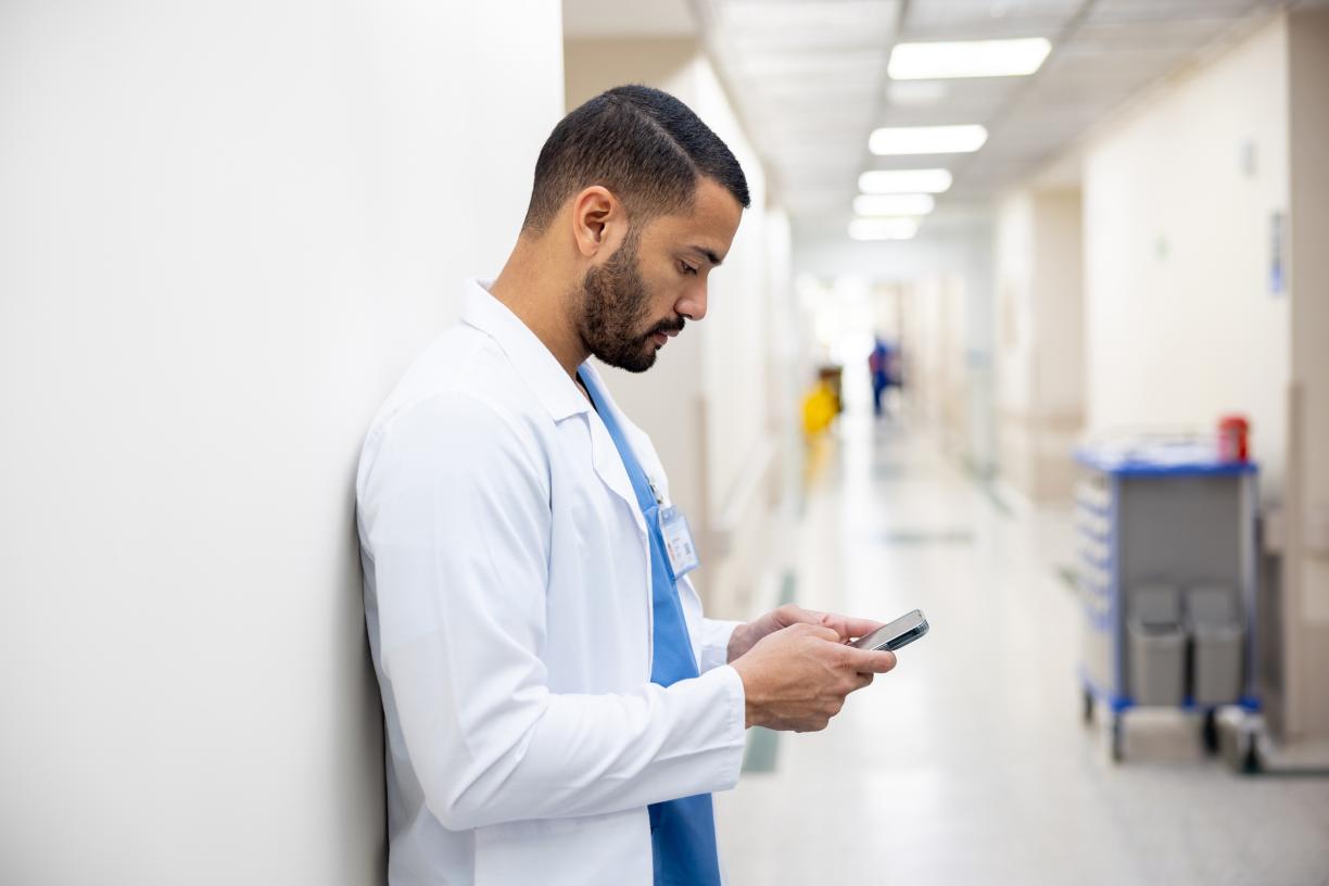 Doctor pauses to text in hospital hallway corridor