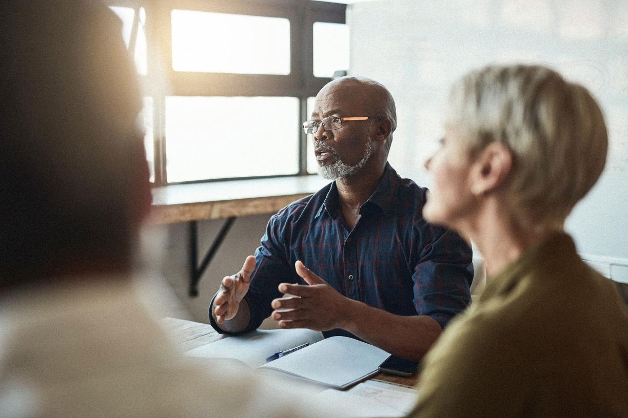 A group of people meeting in a sunlit room. 