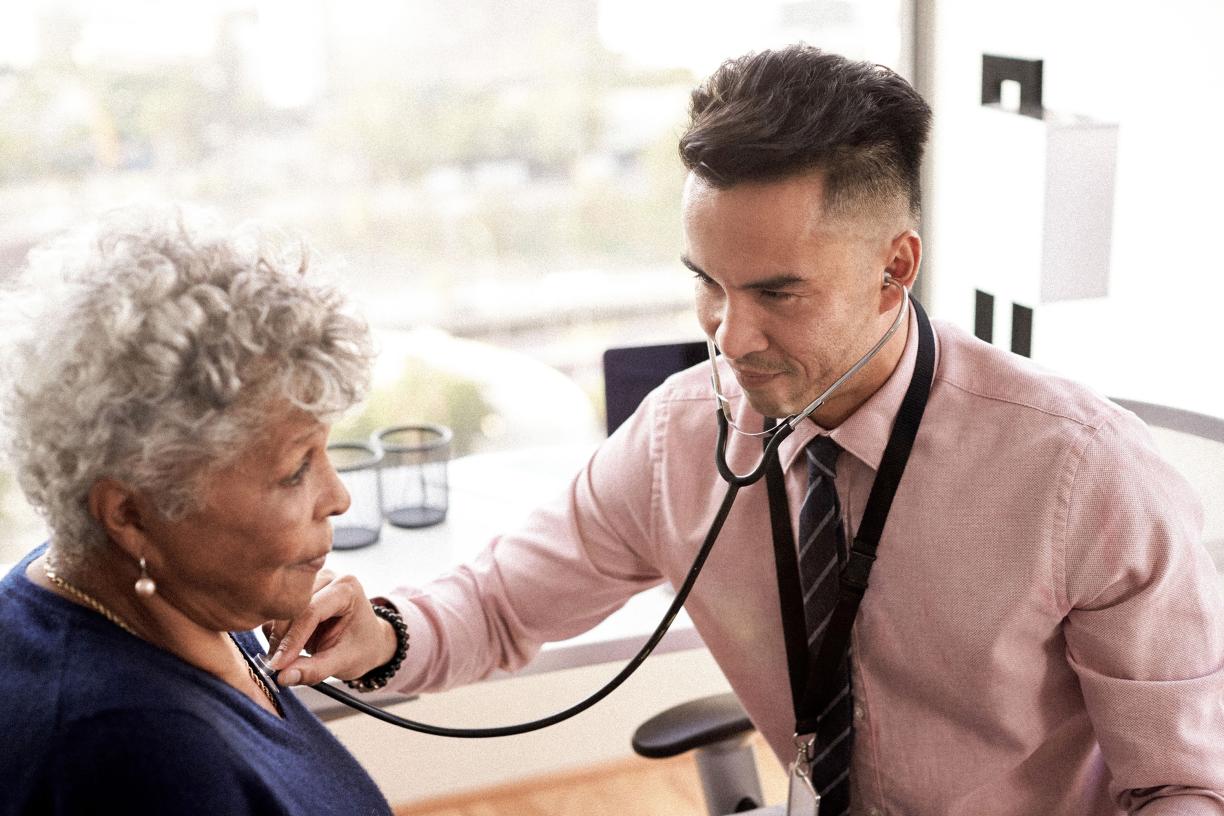 Doctor listening to an elderly patients chest with a stethoscope.