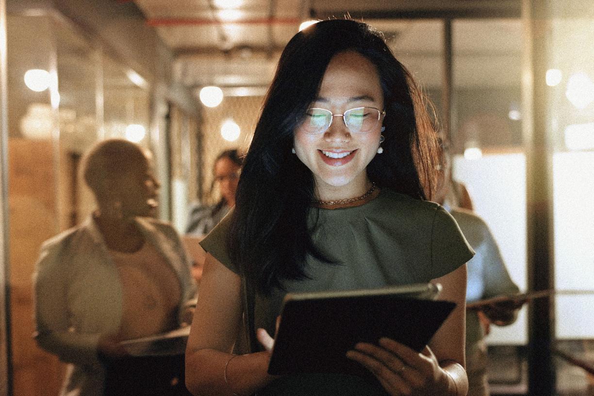 An individual smiling while looking at an ipad. 