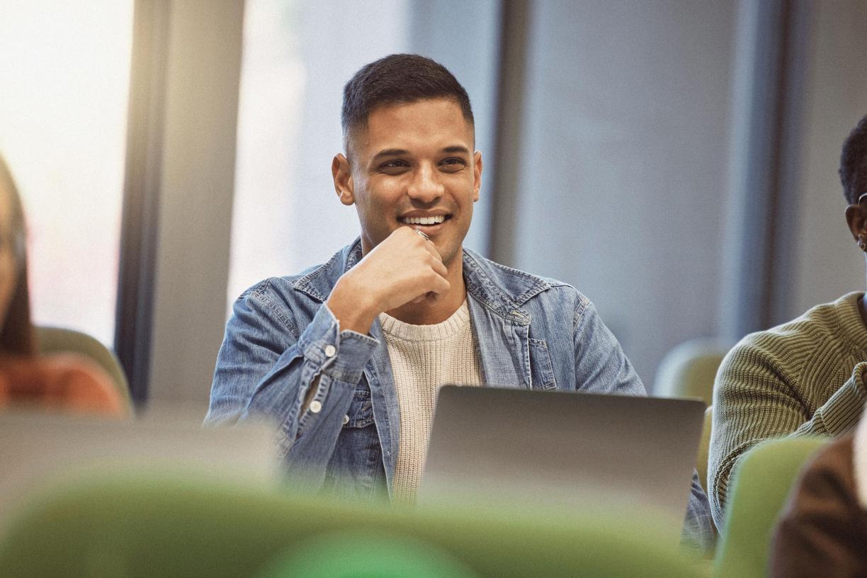 An inidividual sitting in a group setting with a laptop. 